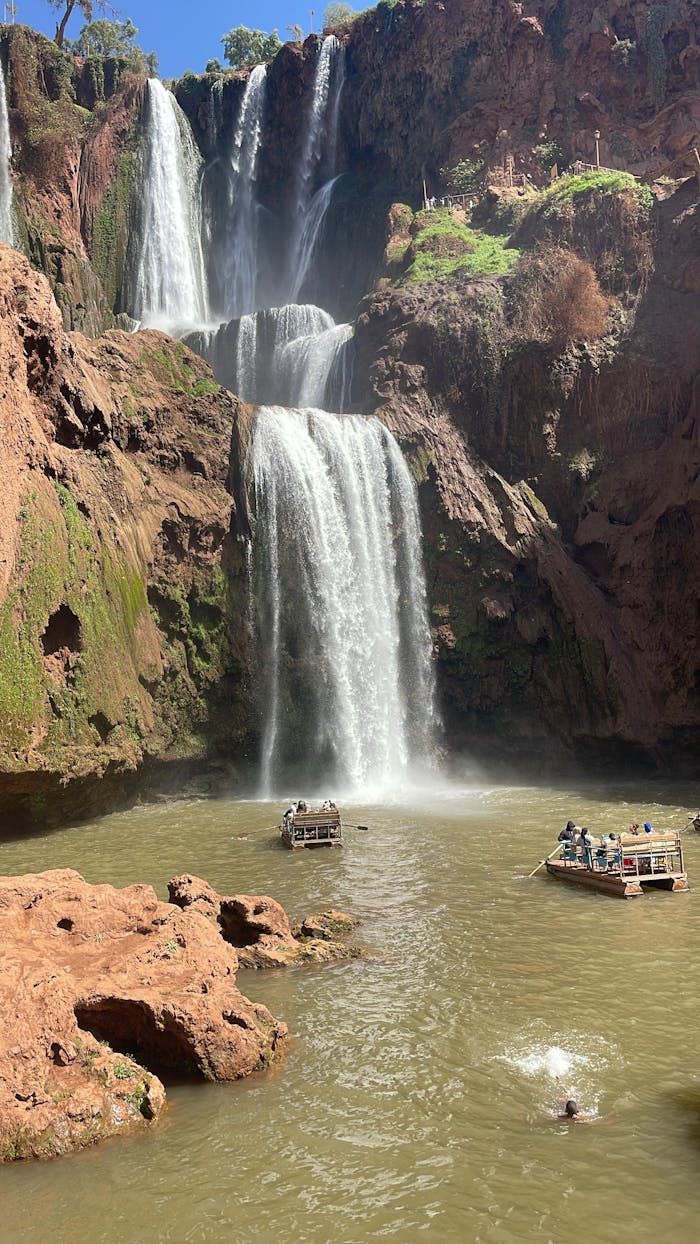 our-stories Capture of Ouzoud Waterfalls with tourists enjoying boat rides under the bright sun.