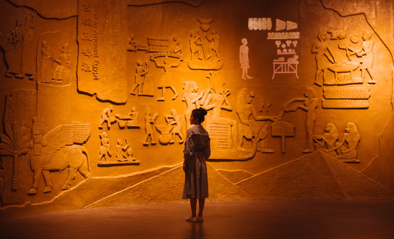 services-04 Back view of anonymous female traveler standing near ancient wall with Egyptian engraving